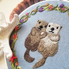 a close up of a embroidery on a piece of cloth with an image of two otters hugging each other