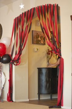 red, black and white streamers are hanging from the ceiling in front of a doorway