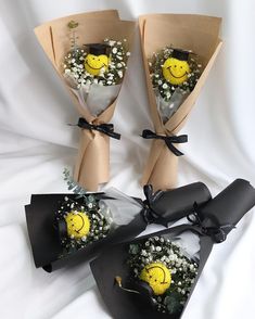 three bouquets with flowers in the shape of smiley faces are on a white sheet