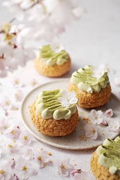 three cookies with green frosting and white flowers on the table next to each other