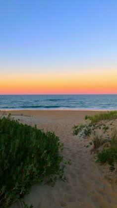 an empty beach at sunset with the ocean in the background