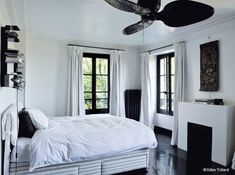 a bedroom with white walls and flooring has a ceiling fan in the middle of the room