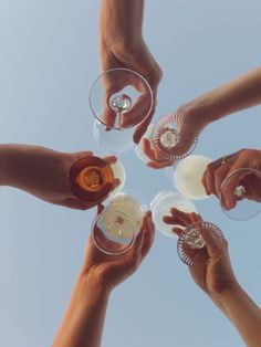 four people are holding wine glasses in the middle of a toasting circle with their hands