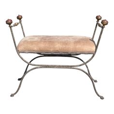 an iron bench with two candles on it's legs and a beige seat cushion