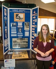 a woman standing in front of a display case with information about women's history