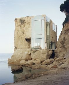 an unusual house built into the side of a cliff by the water's edge