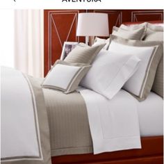 a bed with white sheets and pillows on top of it