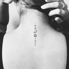 the back of a woman's neck with small tattoos on it