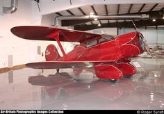 a red airplane sitting on top of a white floor