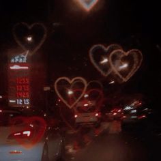 cars driving down the street at night with hearts drawn on it's windshields