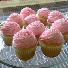 cupcakes with pink frosting sitting on a glass plate