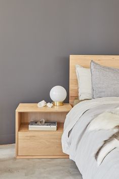 a bed sitting next to a night stand on top of a wooden table in a bedroom