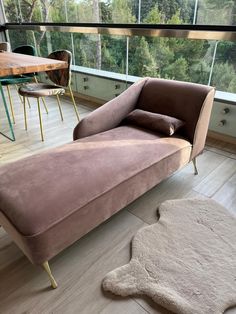 a living room with a chaise lounge chair and rug on the floor next to a large window