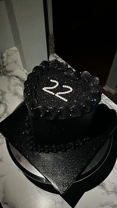 a black heart shaped cake sitting on top of a table