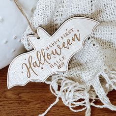 a wooden sign that says happy first halloween hanging from a string on a white cloth