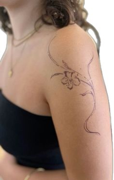 a woman with a flower tattoo on her left arm and shoulder, looking at the camera