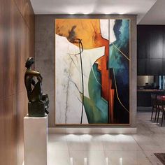 an abstract painting hangs on the wall next to a statue in a modern living room