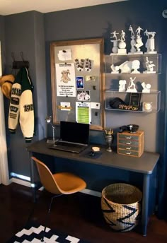 a desk with a laptop computer on top of it next to a wall mounted football memorabilia