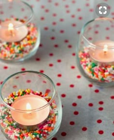 three small glass vases filled with candles and sprinkles on a table