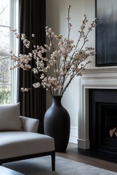 a living room with a couch, chair and vase filled with flowers in front of a fire place