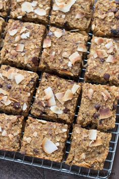 several squares of food sitting on top of a cooling rack with nuts and other toppings