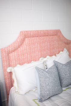 a bed with two pillows sitting on top of it's headboard next to a brick wall