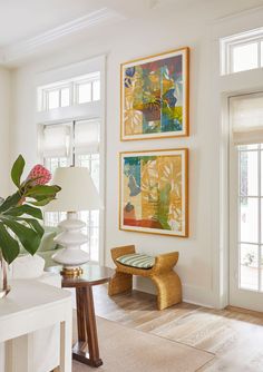 a living room filled with furniture and paintings on the wall next to a table topped with a lamp