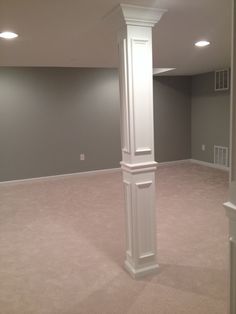 an empty room with a tall white column in the center and carpet on the floor