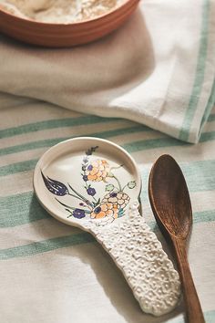 a wooden spoon sitting on top of a plate next to a bowl with food in it