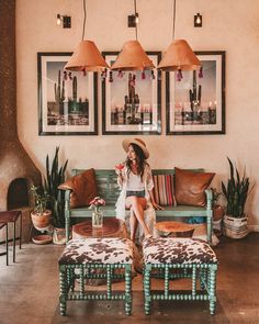 a woman sitting on top of a couch in a living room next to potted plants