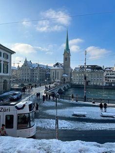 people are walking on the sidewalk in front of some buildings and a bridge with a clock tower