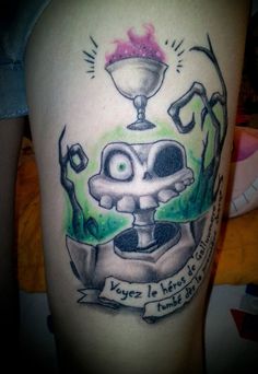 a tattoo on the leg of a person with an image of a skull and a cup