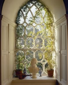 an arched window with potted plants on the ledge and vases in front of it