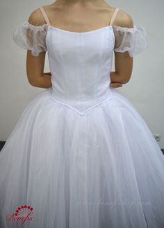 a woman is wearing a white dress with ruffles on the shoulders and shoulder