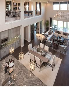 a large open concept living and dining room area with high ceilings, wood flooring and white furniture