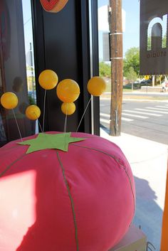 there is a large pink pillow with yellow balloons on it and some green sticks sticking out of the top