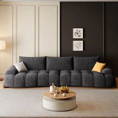 a modern living room with grey couches and yellow pillows on the coffee table in front of it