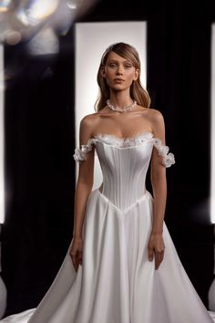 a woman in a white wedding dress standing on a runway