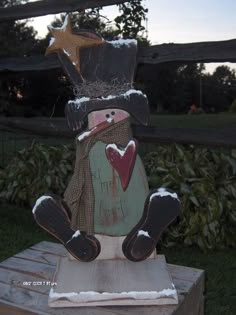 a snowman made out of wood sitting on top of a wooden box