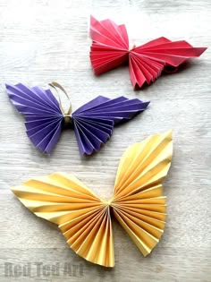 three different colored paper butterflies sitting on top of a table