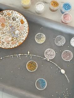 some beads are sitting on a table next to a plate and bowls filled with beads