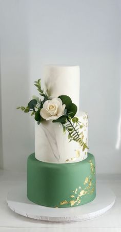 a white and green wedding cake with flowers on top