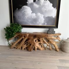 a wooden table sitting on top of a hard wood floor next to a painting and potted plant