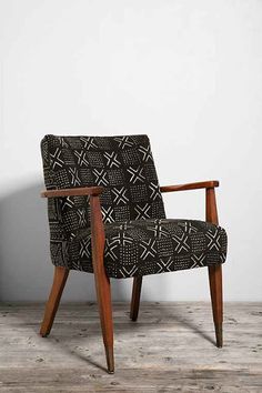 a black and white patterned chair sitting on top of a wooden floor next to a wall