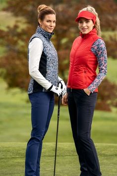 two women standing next to each other on a golf course