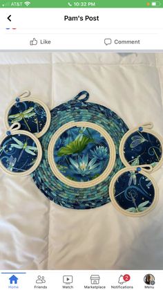 three blue plates and four coasters on a white sheet with green leaves in the center