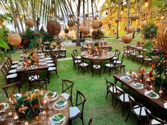 an outdoor dining area with tables and chairs set up for a meal on the grass