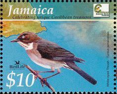 a stamp with a bird sitting on a branch in front of the map of jamaica