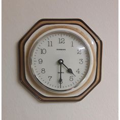 an analog clock mounted on the side of a wall with wood trim around it's edges