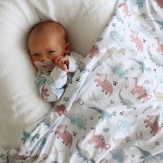 a baby laying on top of a bed covered in blankets